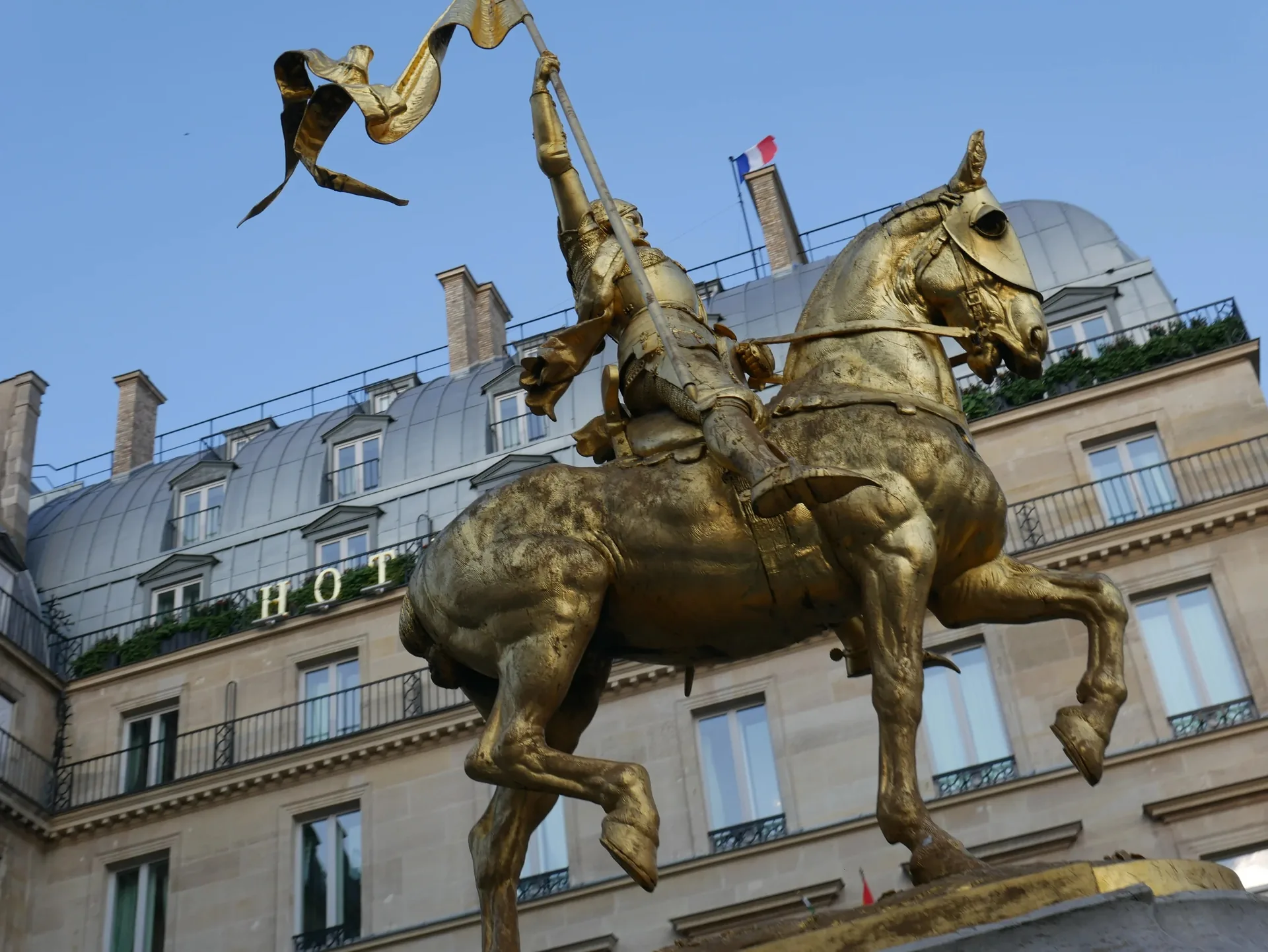 Statue dorée de Jeanne d'Arc à cheval devant un hôtel parisien