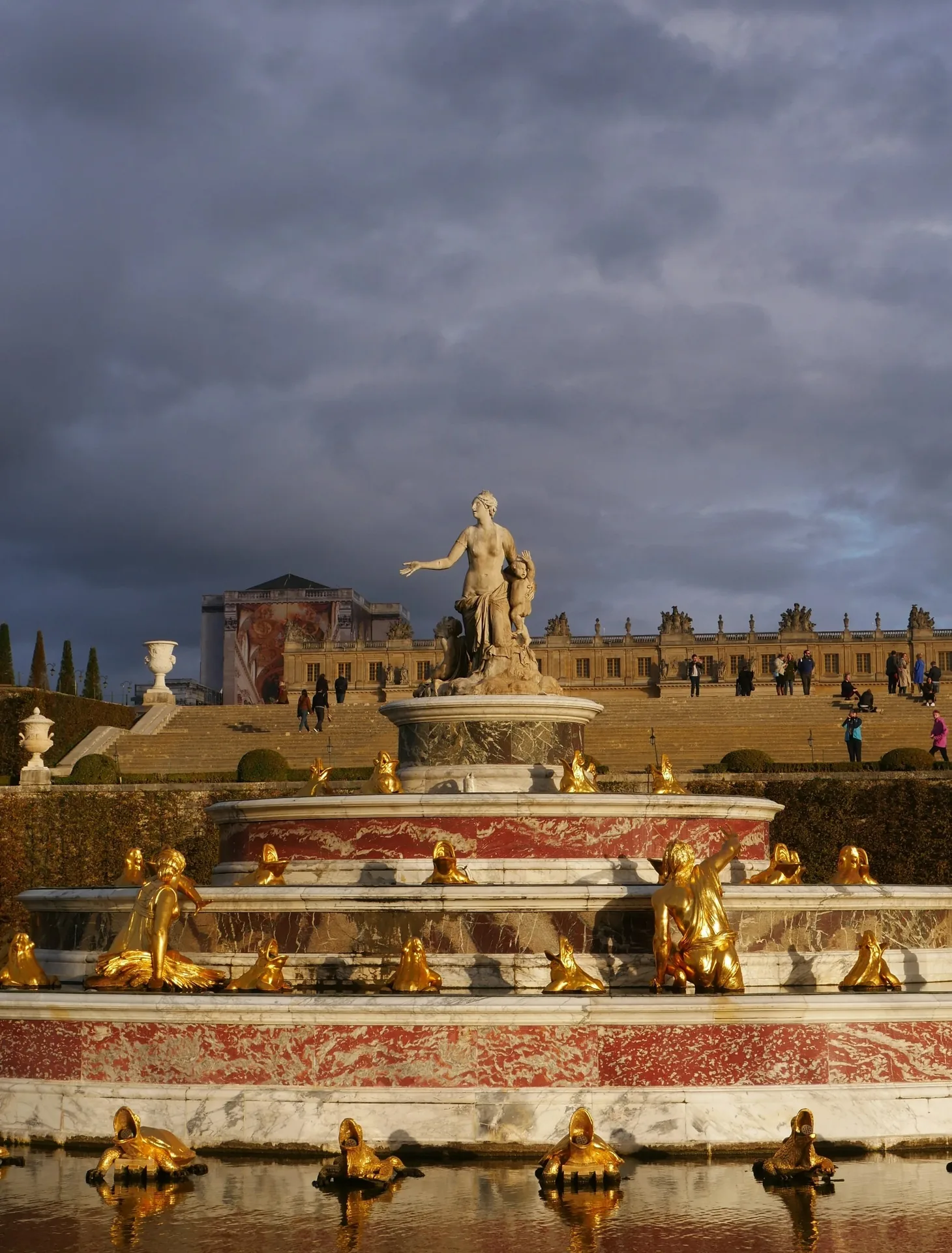 Fontaine de Latone à Versailles avec statues dorées sous un ciel d'orage dramatique
