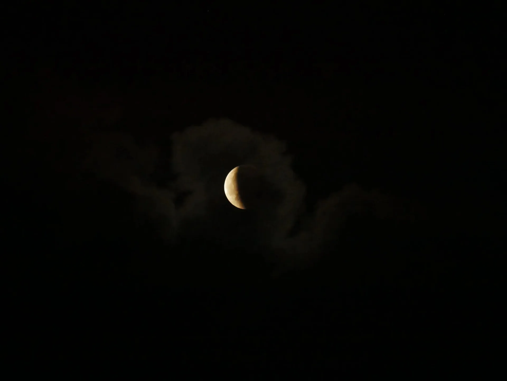 Lune en croissant partiellement voilée par des nuages dans la nuit noire