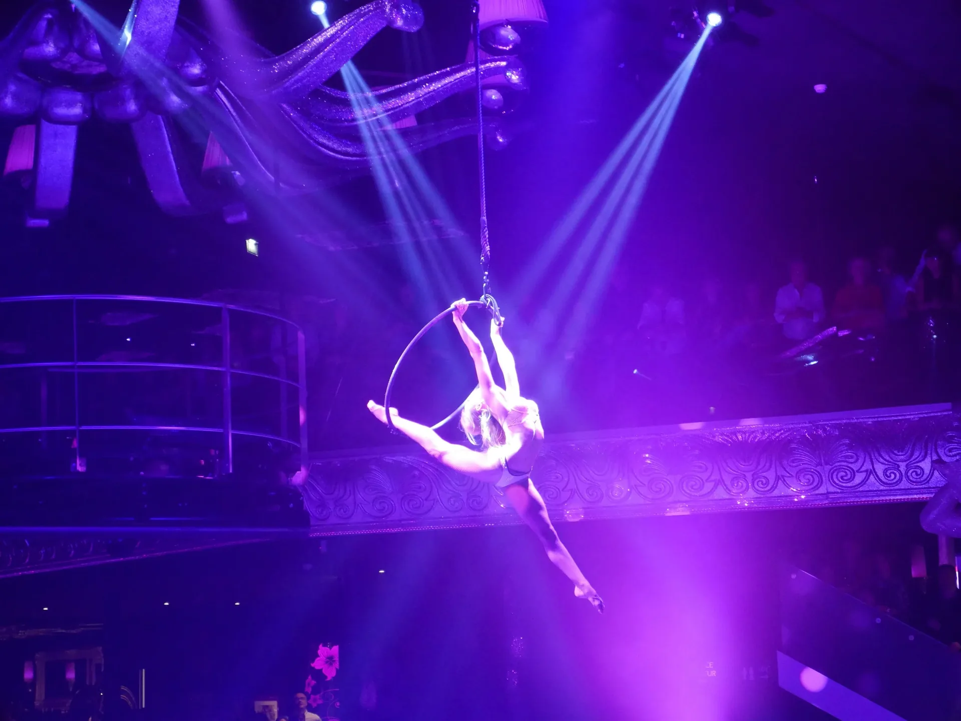 Acrobate en équilibre sur un cerceau aérien lors d'un spectacle de cabaret sous lumière violette